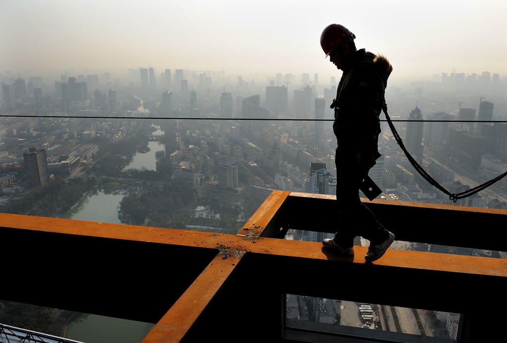 Chinese construction worker walking along a beam.